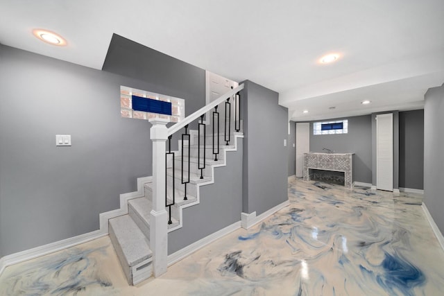 staircase with concrete flooring and a fireplace