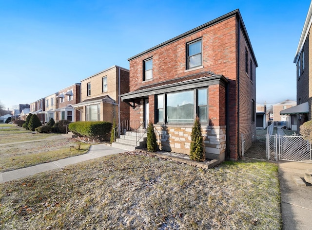 view of front of home with a gate, fence, brick siding, stone siding, and a residential view