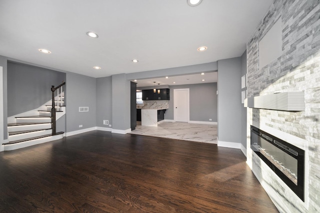 living room with dark hardwood / wood-style floors and a stone fireplace