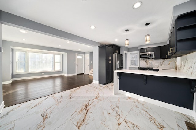 kitchen with pendant lighting, a breakfast bar, backsplash, kitchen peninsula, and stainless steel appliances