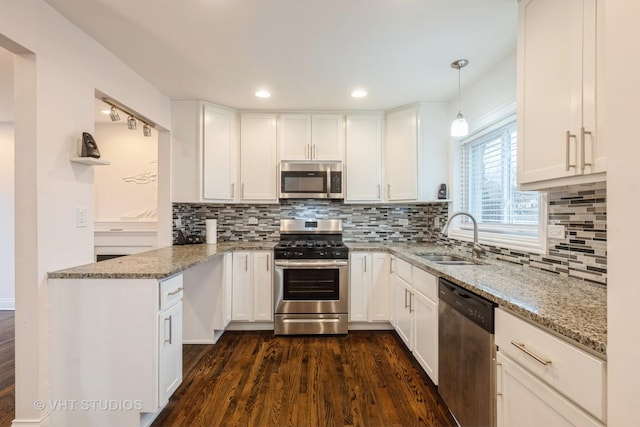 kitchen featuring light stone countertops, white cabinetry, sink, pendant lighting, and appliances with stainless steel finishes