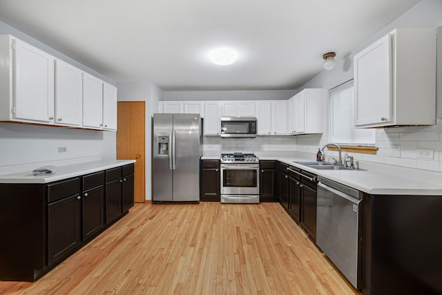 kitchen with sink, white cabinets, light hardwood / wood-style flooring, and appliances with stainless steel finishes