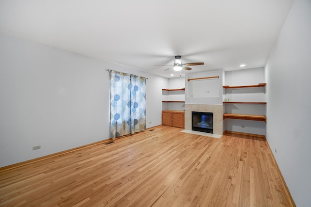 unfurnished living room featuring a fireplace, light hardwood / wood-style floors, and ceiling fan