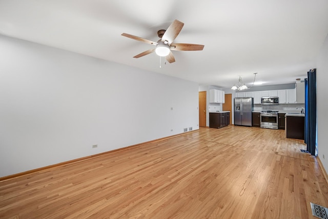 unfurnished living room featuring ceiling fan with notable chandelier, light hardwood / wood-style flooring, and sink