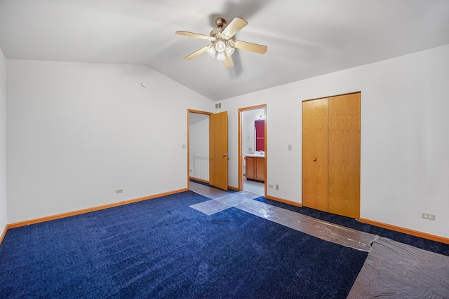 unfurnished bedroom with ensuite bathroom, vaulted ceiling, ceiling fan, dark colored carpet, and a closet