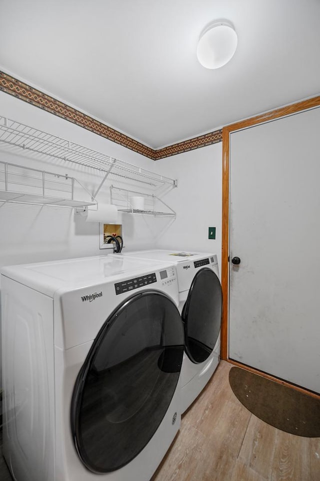 clothes washing area featuring washing machine and dryer and light hardwood / wood-style floors