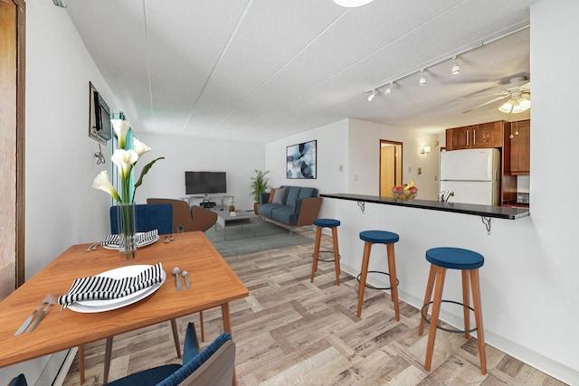 kitchen with kitchen peninsula, a textured ceiling, ceiling fan, white refrigerator, and a breakfast bar area