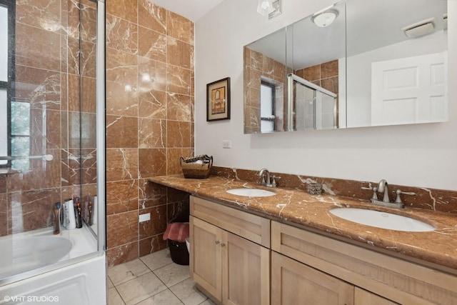 bathroom with tile patterned flooring, vanity, enclosed tub / shower combo, and tile walls