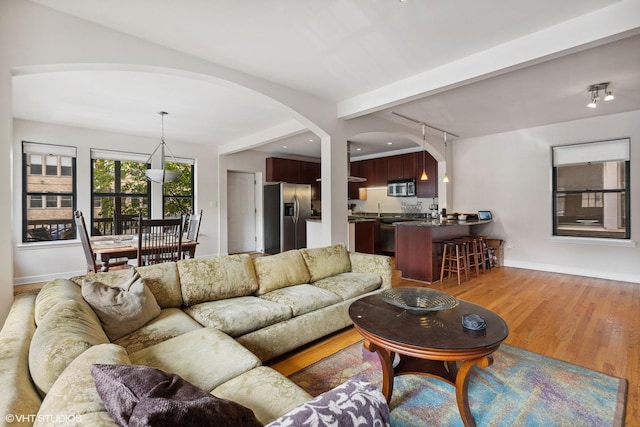 living room with beamed ceiling and light hardwood / wood-style floors