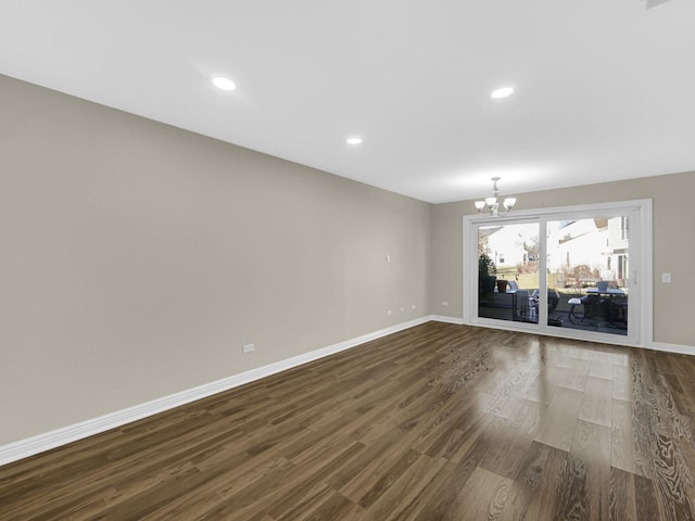 unfurnished room with a chandelier and dark hardwood / wood-style floors