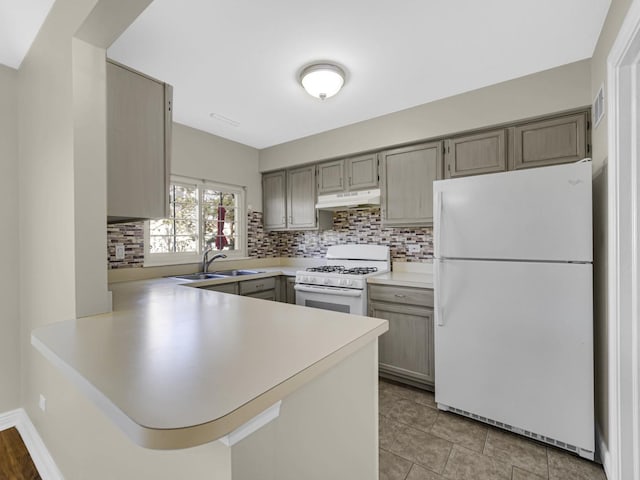 kitchen with decorative backsplash, sink, white appliances, and kitchen peninsula