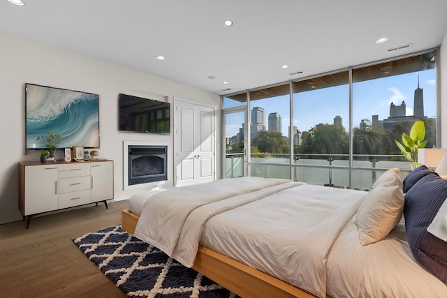 bedroom with a wall of windows and hardwood / wood-style flooring