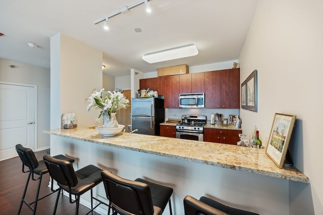 kitchen with kitchen peninsula, a breakfast bar, stainless steel appliances, and dark hardwood / wood-style flooring