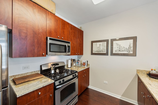 kitchen with appliances with stainless steel finishes, dark hardwood / wood-style flooring, and light stone counters