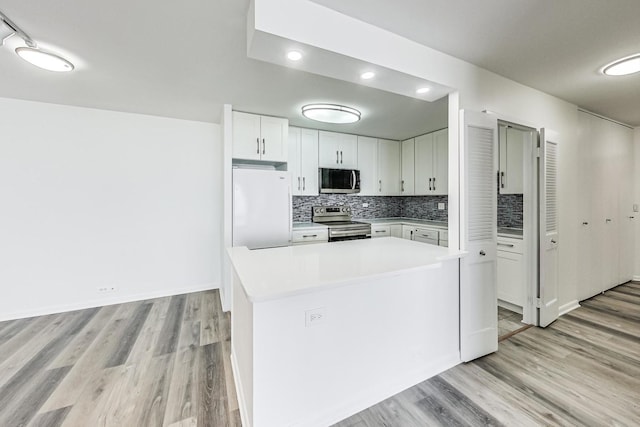 kitchen featuring white cabinetry, tasteful backsplash, a center island, appliances with stainless steel finishes, and light hardwood / wood-style floors