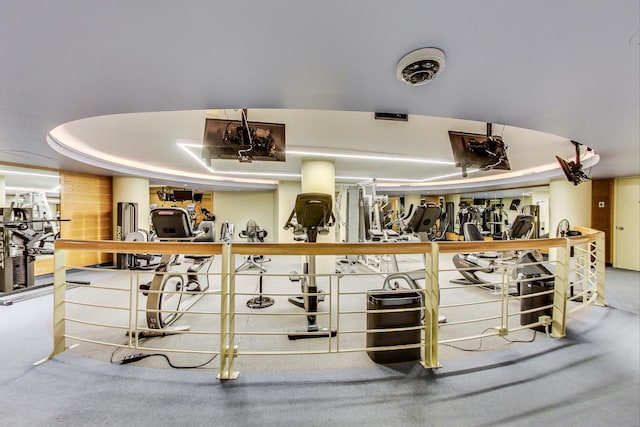 workout area with a tray ceiling and carpet floors