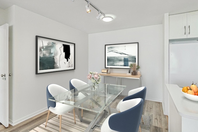 dining space with track lighting and light hardwood / wood-style flooring