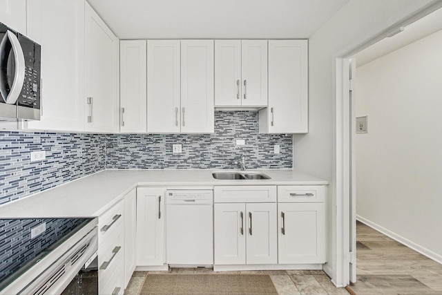 kitchen with appliances with stainless steel finishes, sink, decorative backsplash, and white cabinets