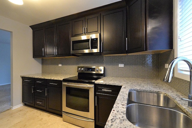 kitchen with backsplash, light stone counters, sink, and stainless steel appliances