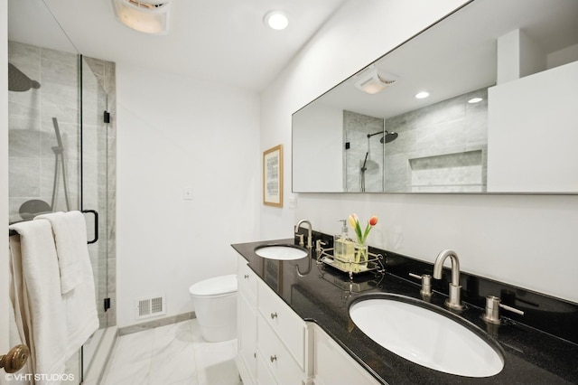 bathroom featuring toilet, vanity, and a shower with shower door