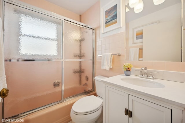 full bathroom with toilet, enclosed tub / shower combo, vanity, tile walls, and tasteful backsplash