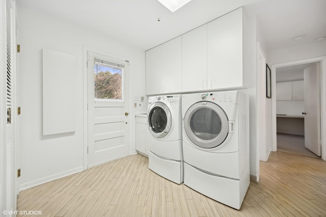 washroom featuring washer and dryer, cabinets, and light wood-type flooring