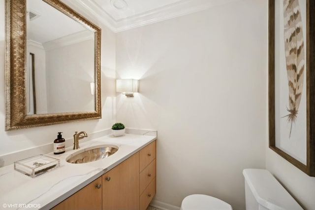 bathroom with toilet, vanity, and ornamental molding