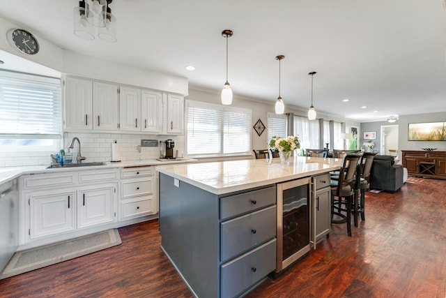 kitchen featuring sink, white cabinets, beverage cooler, a kitchen bar, and a center island