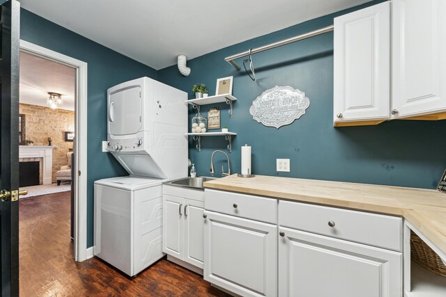 laundry room with dark wood-type flooring, cabinets, and stacked washer / drying machine