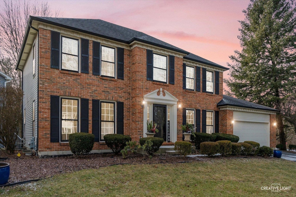 colonial inspired home with a lawn and a garage