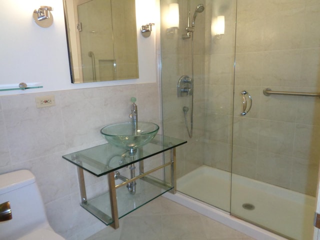 bathroom featuring a shower with door, sink, and tile walls