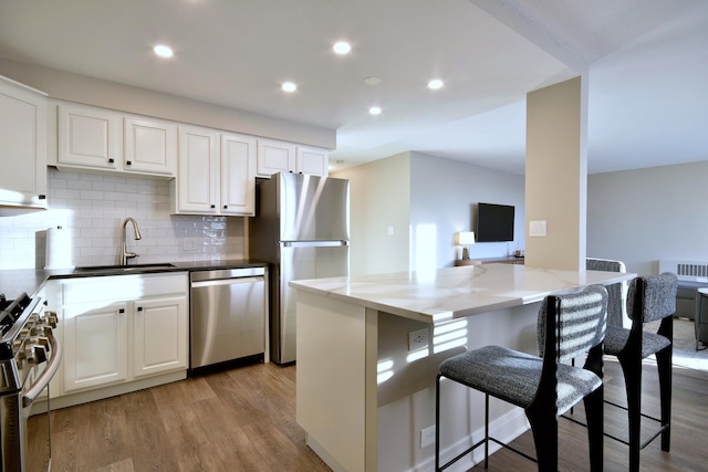 kitchen featuring white cabinets, appliances with stainless steel finishes, dark stone counters, sink, and a breakfast bar