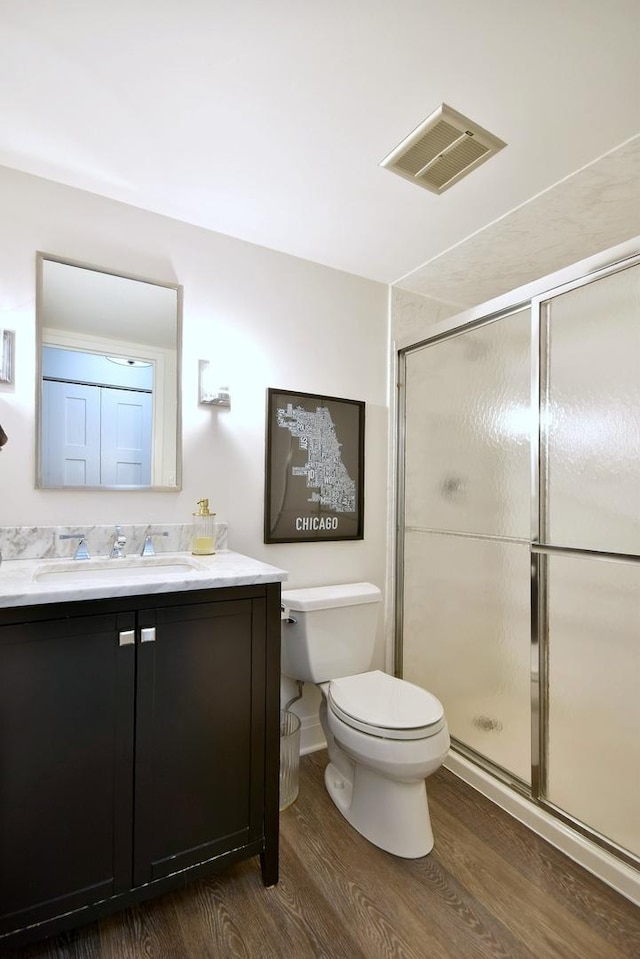 bathroom featuring hardwood / wood-style floors, an enclosed shower, vanity, and toilet