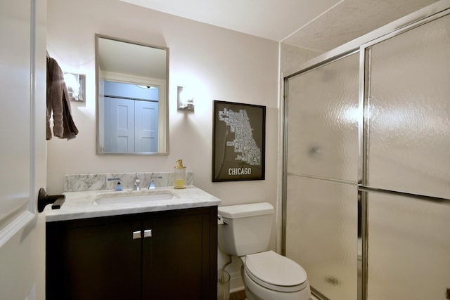 bathroom featuring toilet, a shower with shower door, and vanity