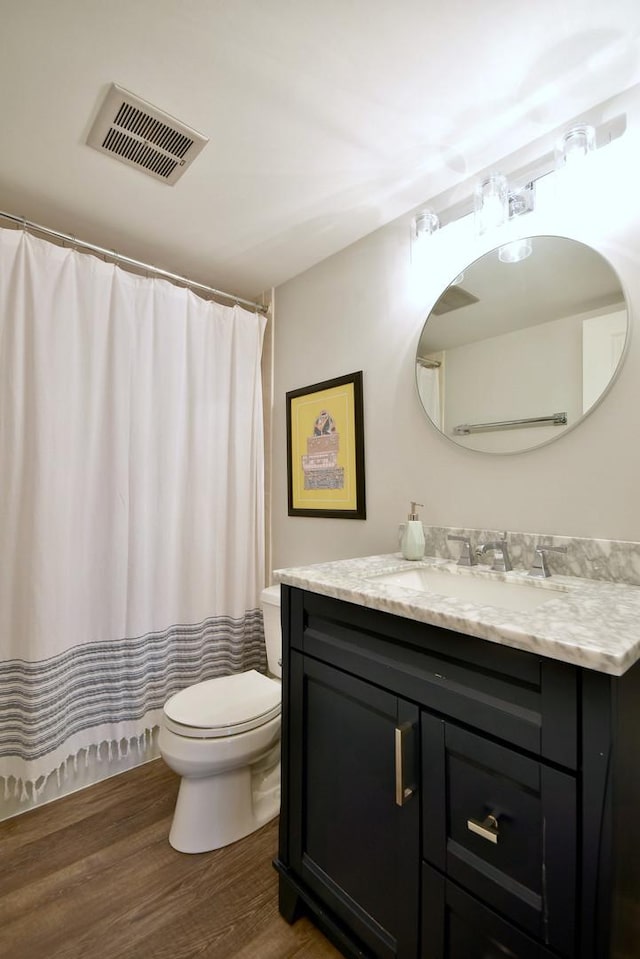 bathroom with wood-type flooring, toilet, and vanity