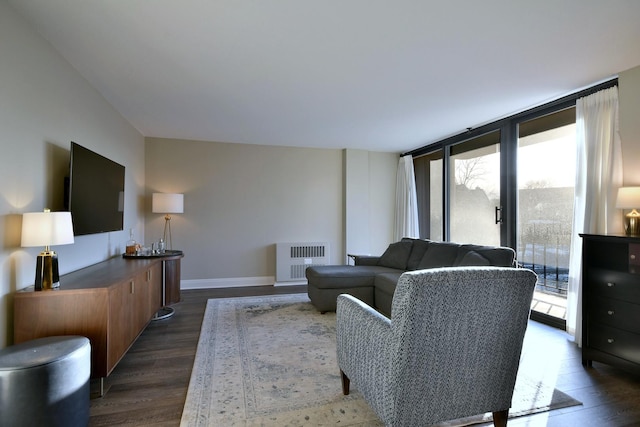 living room featuring dark wood-type flooring, radiator heating unit, and a healthy amount of sunlight