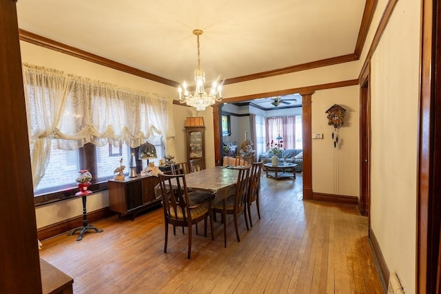 dining space with ceiling fan with notable chandelier, wood-type flooring, ornamental molding, and ornate columns