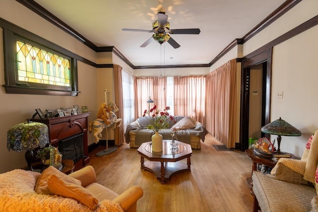 sitting room with light wood-type flooring, ceiling fan, and ornamental molding