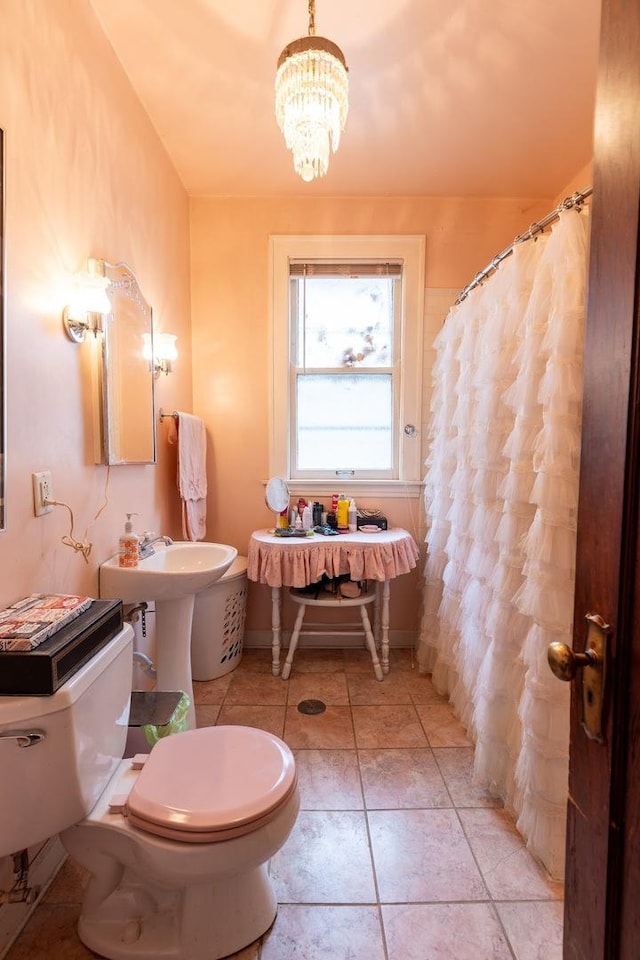 bathroom with tile patterned flooring, toilet, and a chandelier