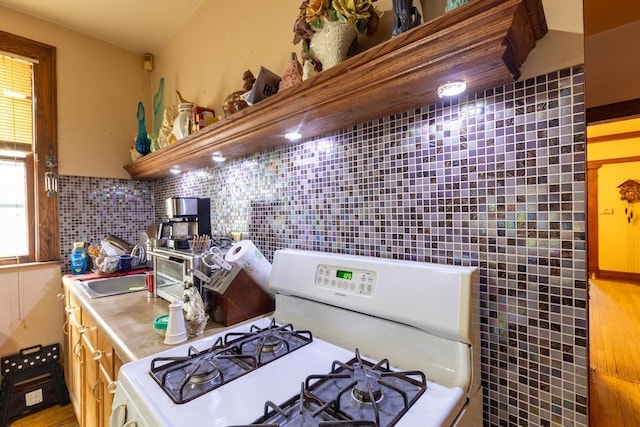 kitchen featuring backsplash, sink, and white gas range oven