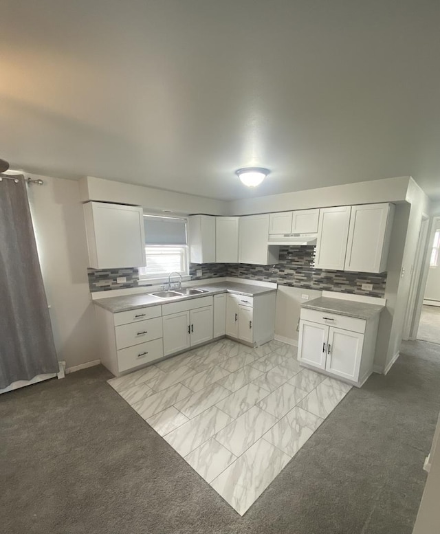 kitchen featuring white cabinets, backsplash, light colored carpet, and sink