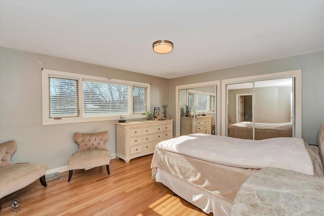 bedroom with light hardwood / wood-style floors and two closets