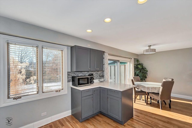 kitchen with light hardwood / wood-style flooring, plenty of natural light, gray cabinetry, and tasteful backsplash