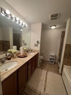 bathroom with a washtub, vanity, and toilet