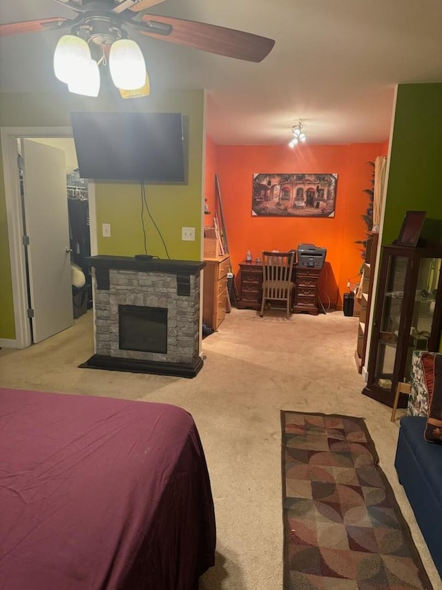 carpeted bedroom with ceiling fan and a fireplace