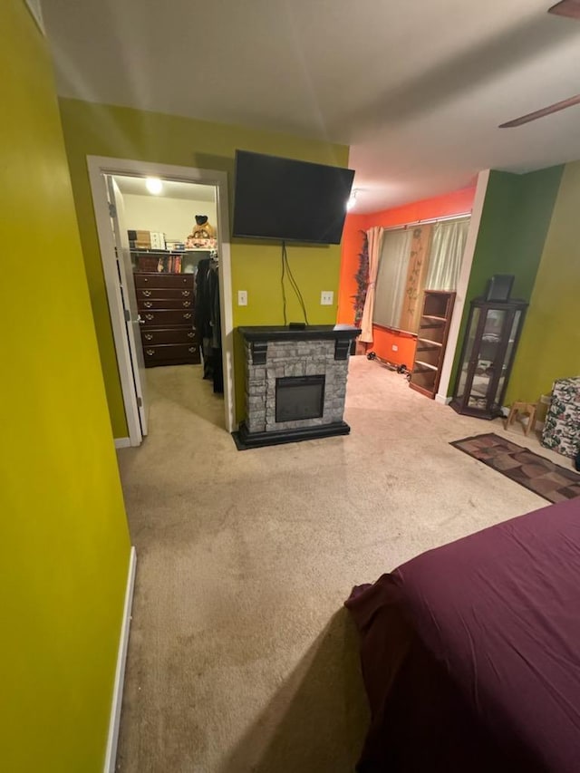 carpeted bedroom with a stone fireplace, a spacious closet, and a closet