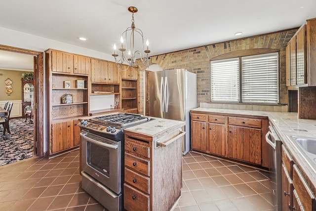 kitchen with tile countertops, hanging light fixtures, appliances with stainless steel finishes, and a chandelier