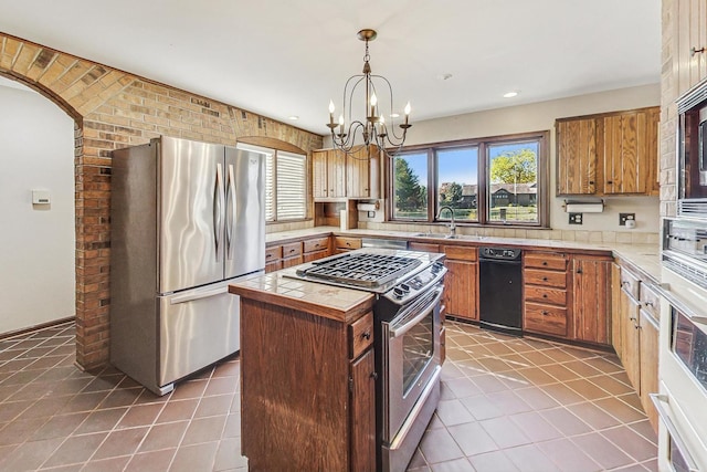 kitchen with hanging light fixtures, stainless steel appliances, a chandelier, a kitchen island, and dark tile patterned flooring