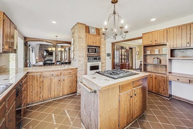 kitchen with tile countertops, a chandelier, stainless steel appliances, and decorative light fixtures