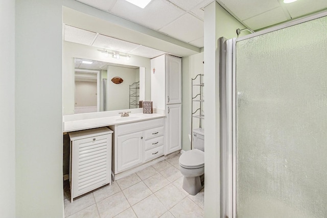 bathroom featuring tile patterned floors, an enclosed shower, a drop ceiling, vanity, and toilet